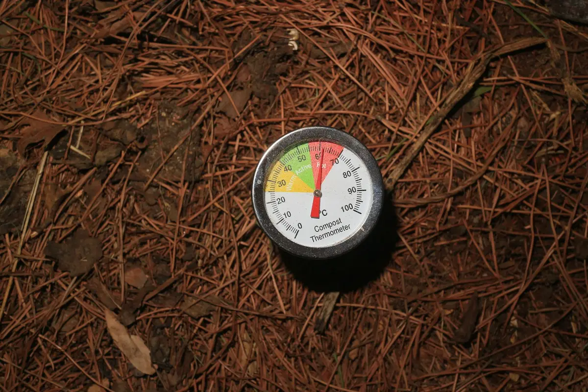 Tas de compost en cours de brassage avec fourche, montrant la matière en décomposition