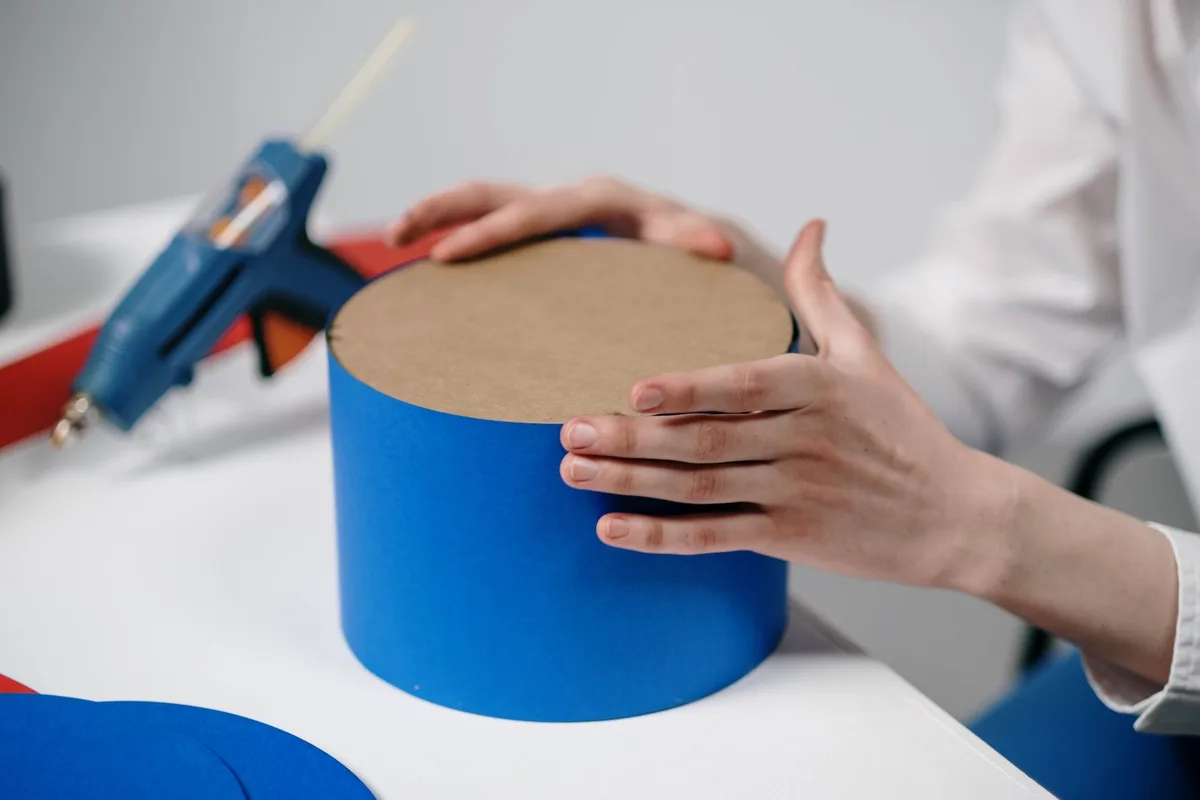 Mains assemblant des pétales en papier autour d'un cœur pour créer une fleur