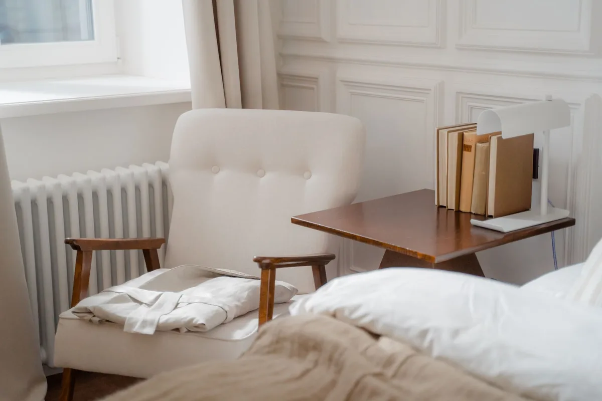 Petit coin lecture avec fauteuil, luminaire doux et panier tressé dans une chambre blanche