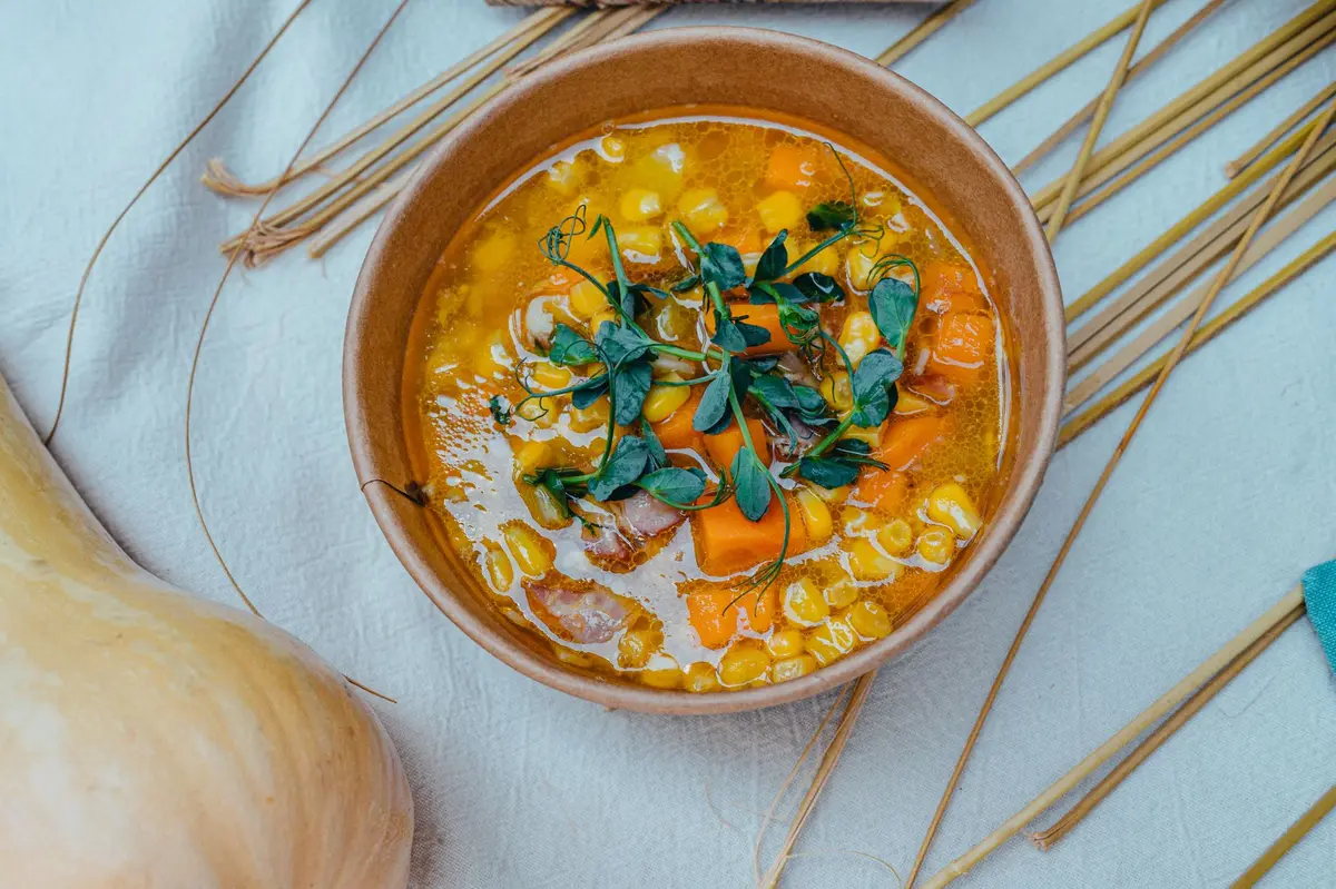 Bol de soupe maison avec légumes racines et garnitures dans une cuisine automnale