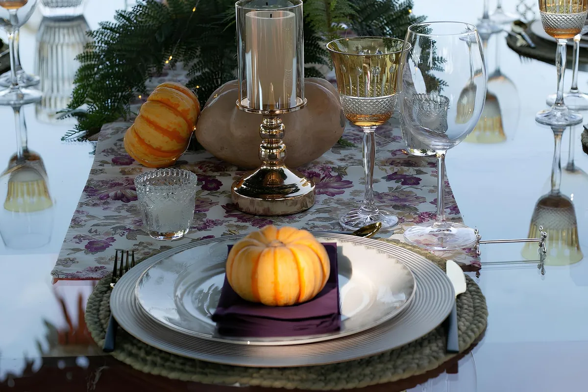 Table de Thanksgiving avec centre de table orné de branches, bougies et éléments naturels saisonniers