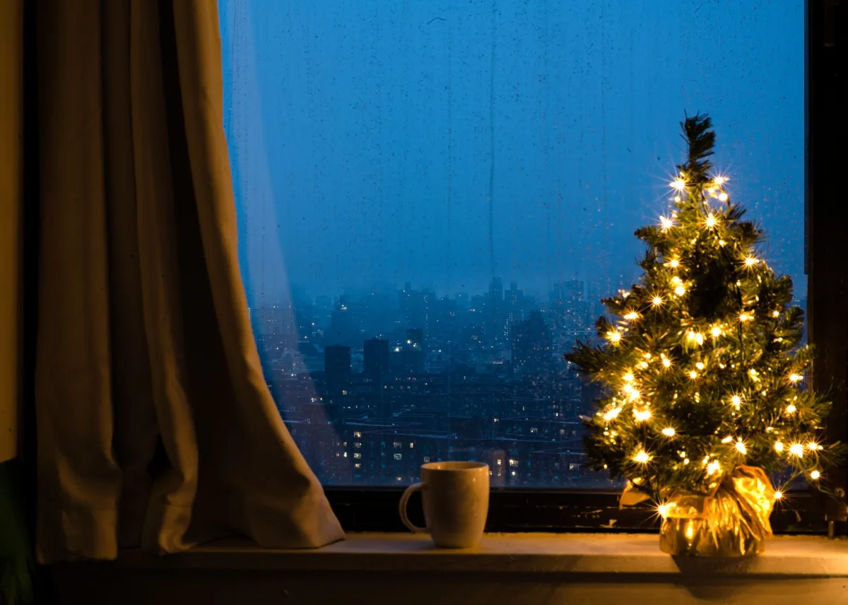 Petit sapin de Noël compact dans un espace restreint avec guirlandes murales discrètes