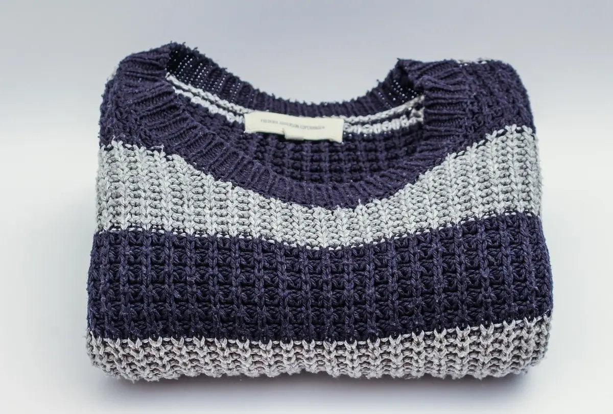 Plaid en laine plié sur une chaise, montrant fibre et finition