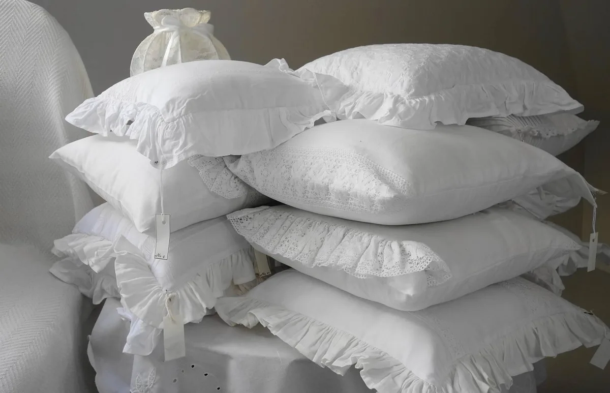 Lit en lin blanc et coussins crème dans une chambre claire