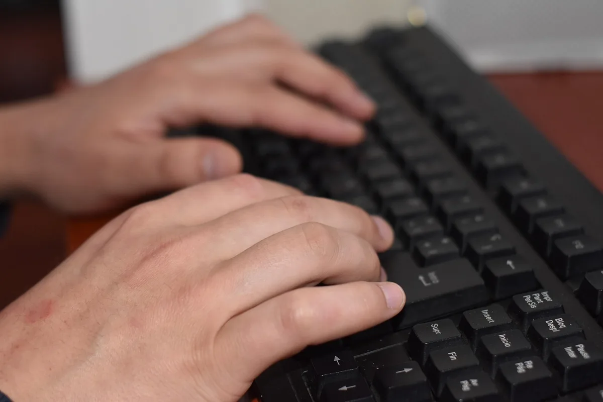 Main montrant une miniature sur un bureau avec écran en arrière-plan